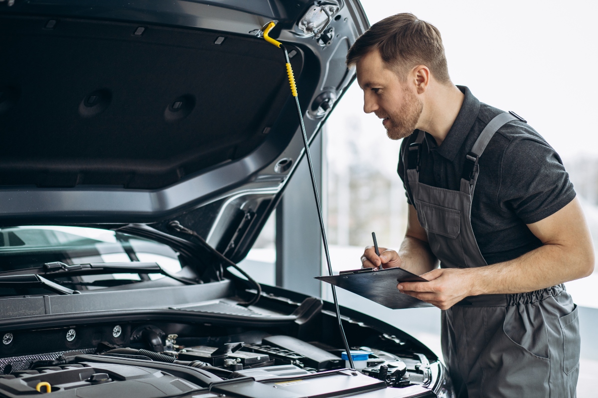 Mechanic checking car following collision repair guide.